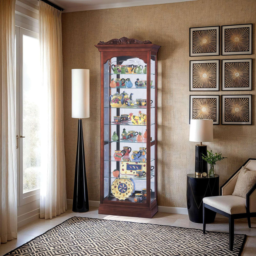 A wooden display cabinet filled with various decorative items, standing in a modern living room with a lamp and seating.
