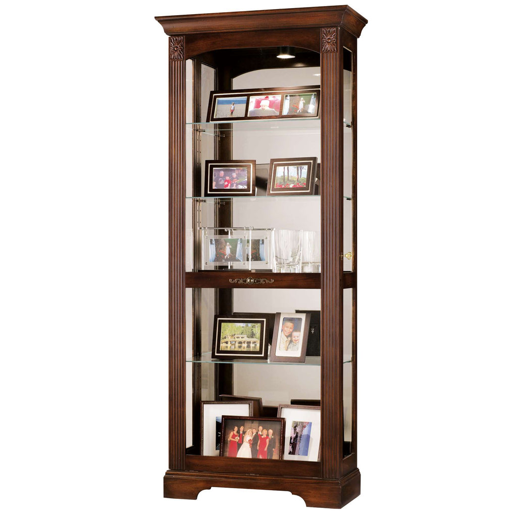 Tall wooden display cabinet with glass shelves showcasing framed photos and glassware