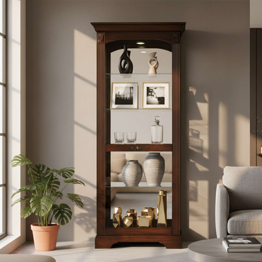 Glass display cabinet with decorative items and framed photos, next to a potted plant and a seating area.