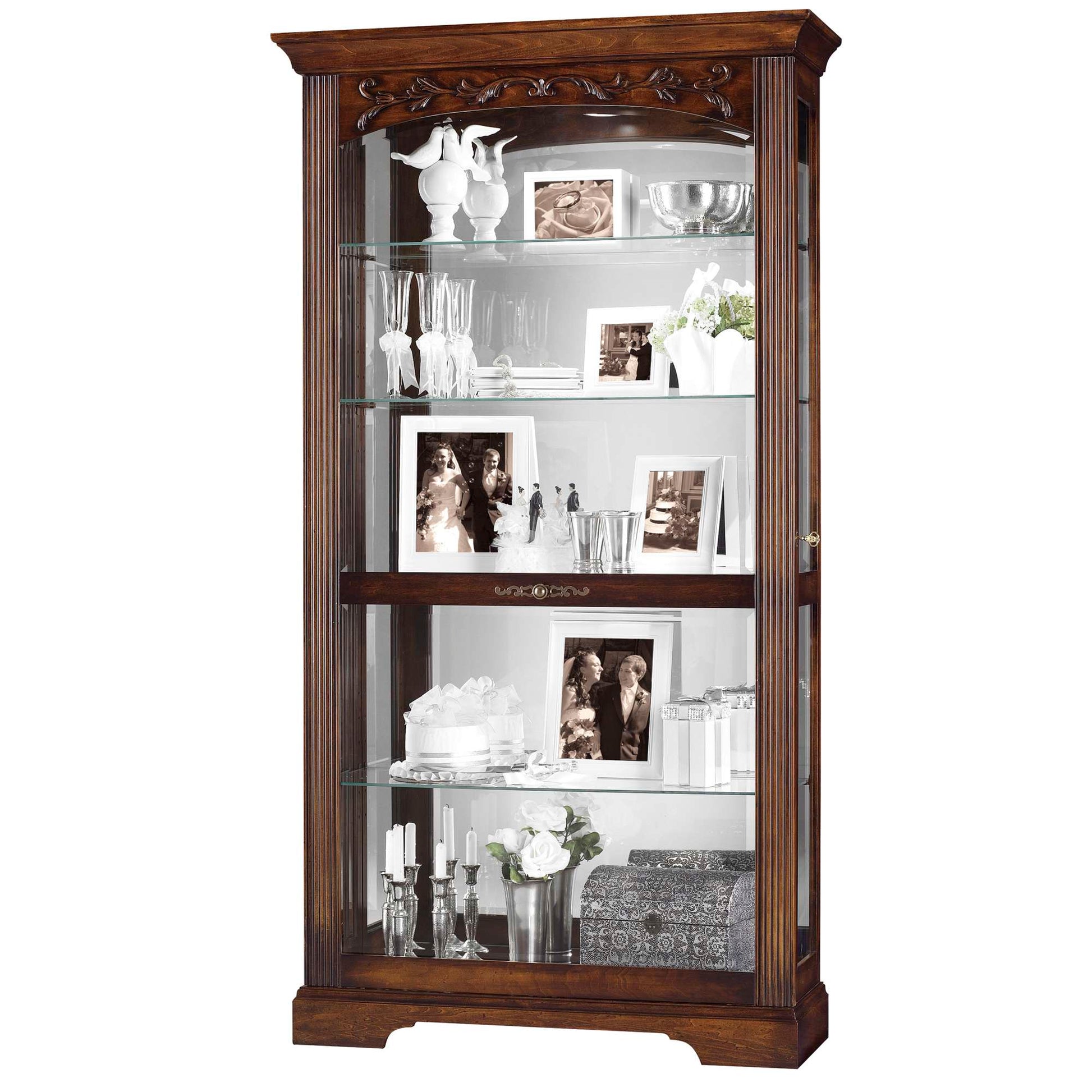 A wooden display cabinet with glass shelves showcasing decorative items and framed photos.