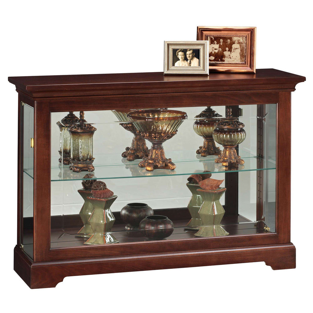 A wooden display cabinet with glass shelves showcasing decorative items and framed photos.