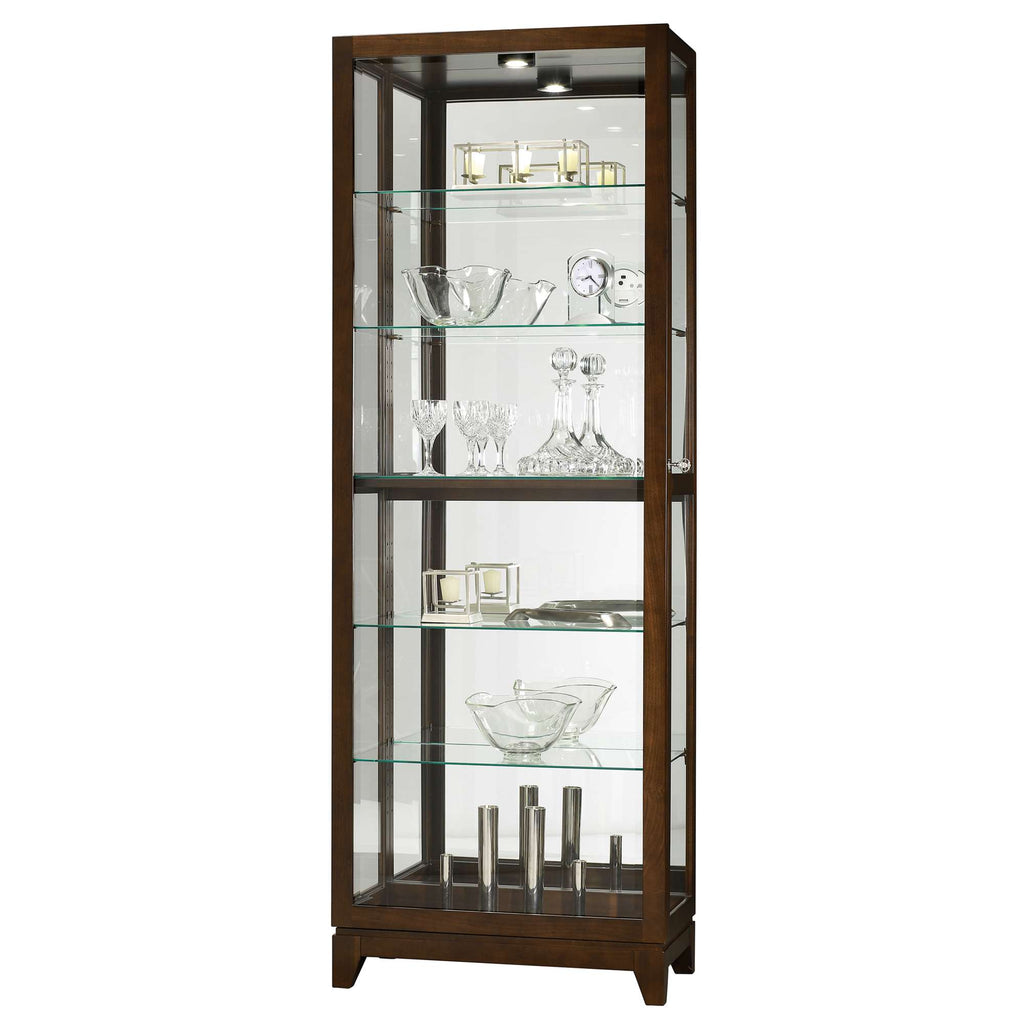 A tall wooden display cabinet with glass shelves showcasing various glassware and decorative items.