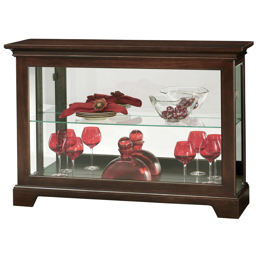 A wooden display cabinet featuring a glass front with red decorative items, including glasses and vases, arranged inside.
