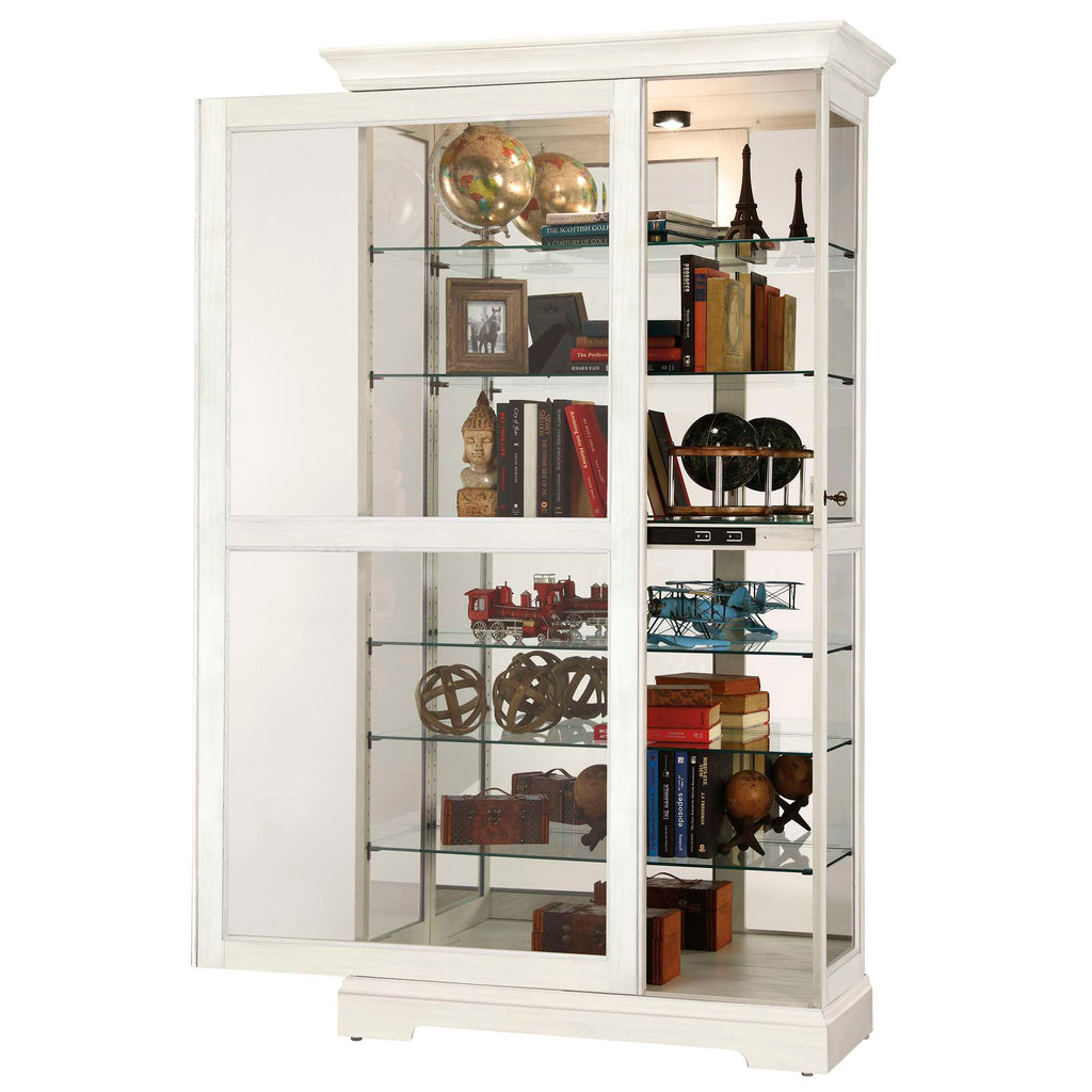 A white display cabinet with glass shelves showcasing decorative items and books.