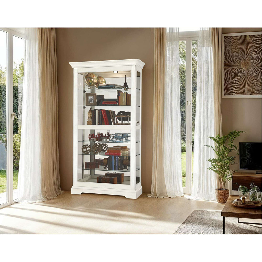 A modern white display cabinet featuring shelves filled with decorative items, positioned beside large windows with natural light streaming in.