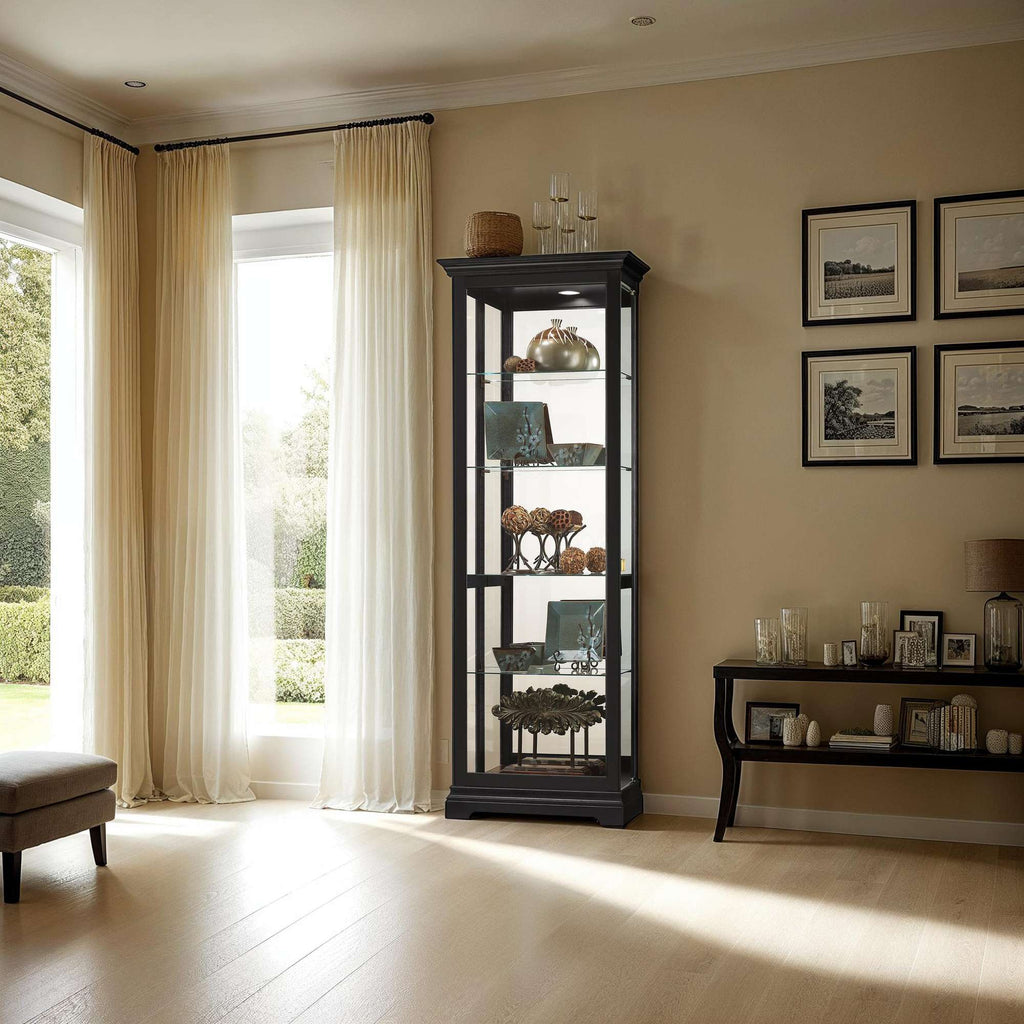 A modern living room featuring a glass display cabinet and a wooden side table with decor, illuminated by natural light from large windows.