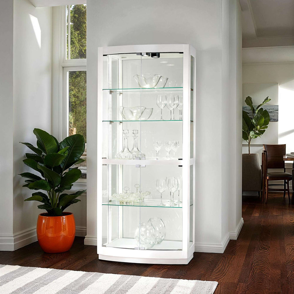 A modern glass display cabinet with shelves showcasing elegant glassware, beside a lush potted plant.
