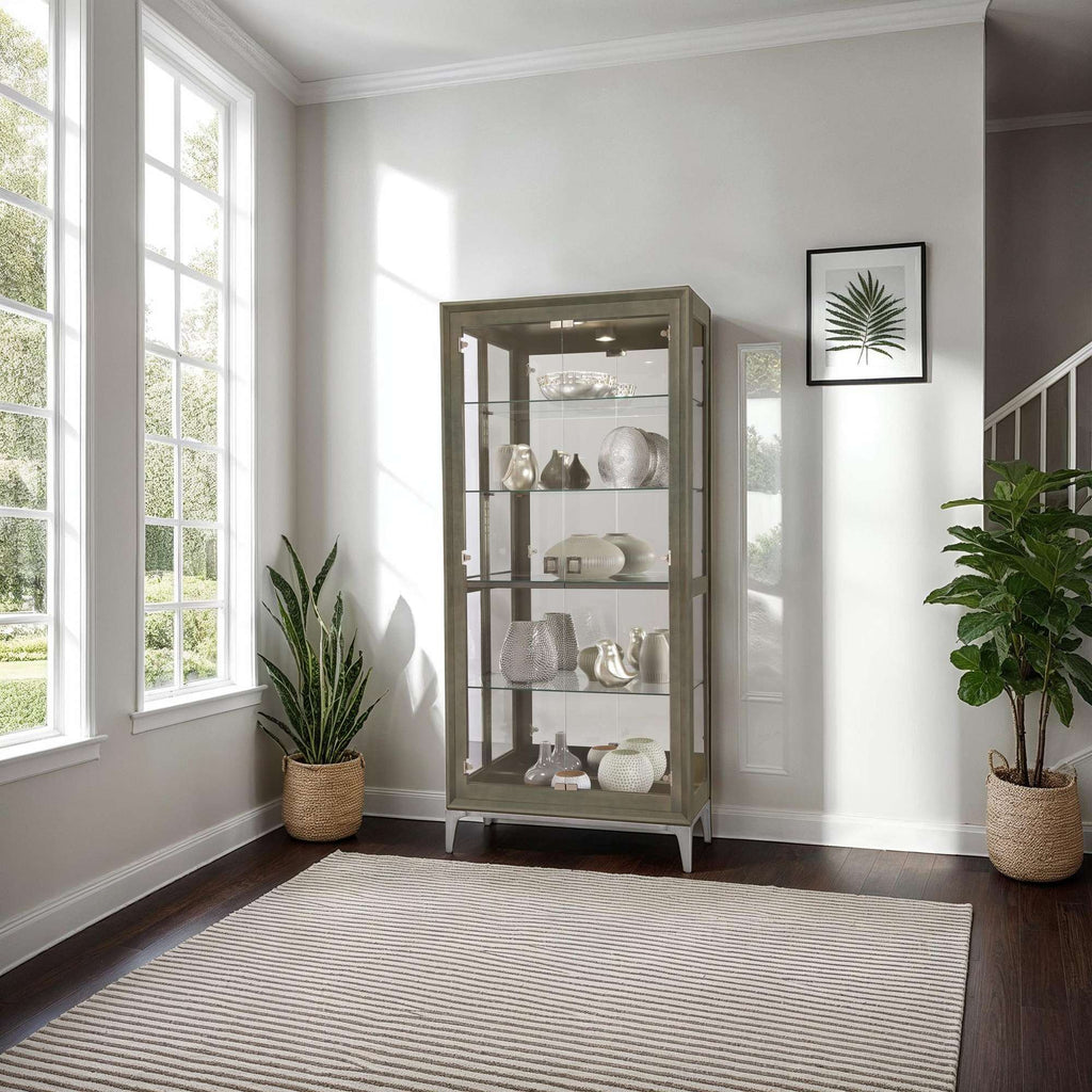 A bright interior featuring a glass display cabinet with decorative objects, surrounded by natural light and houseplants.