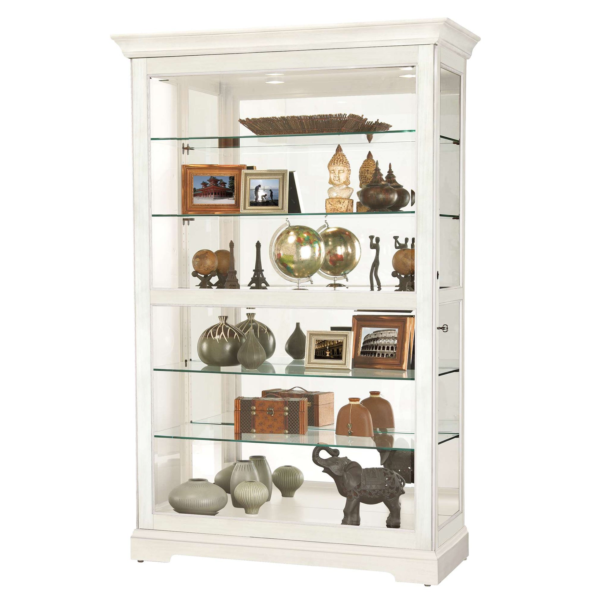 A white display cabinet with glass shelves showcasing various decorative items, including vases, globes, and photo frames.