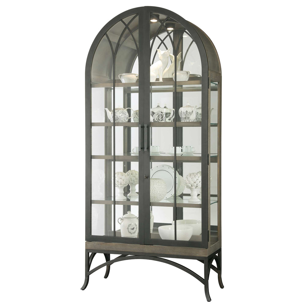 A tall, arched display cabinet made of glass and metal, showcasing various decorative dishes and collectibles.