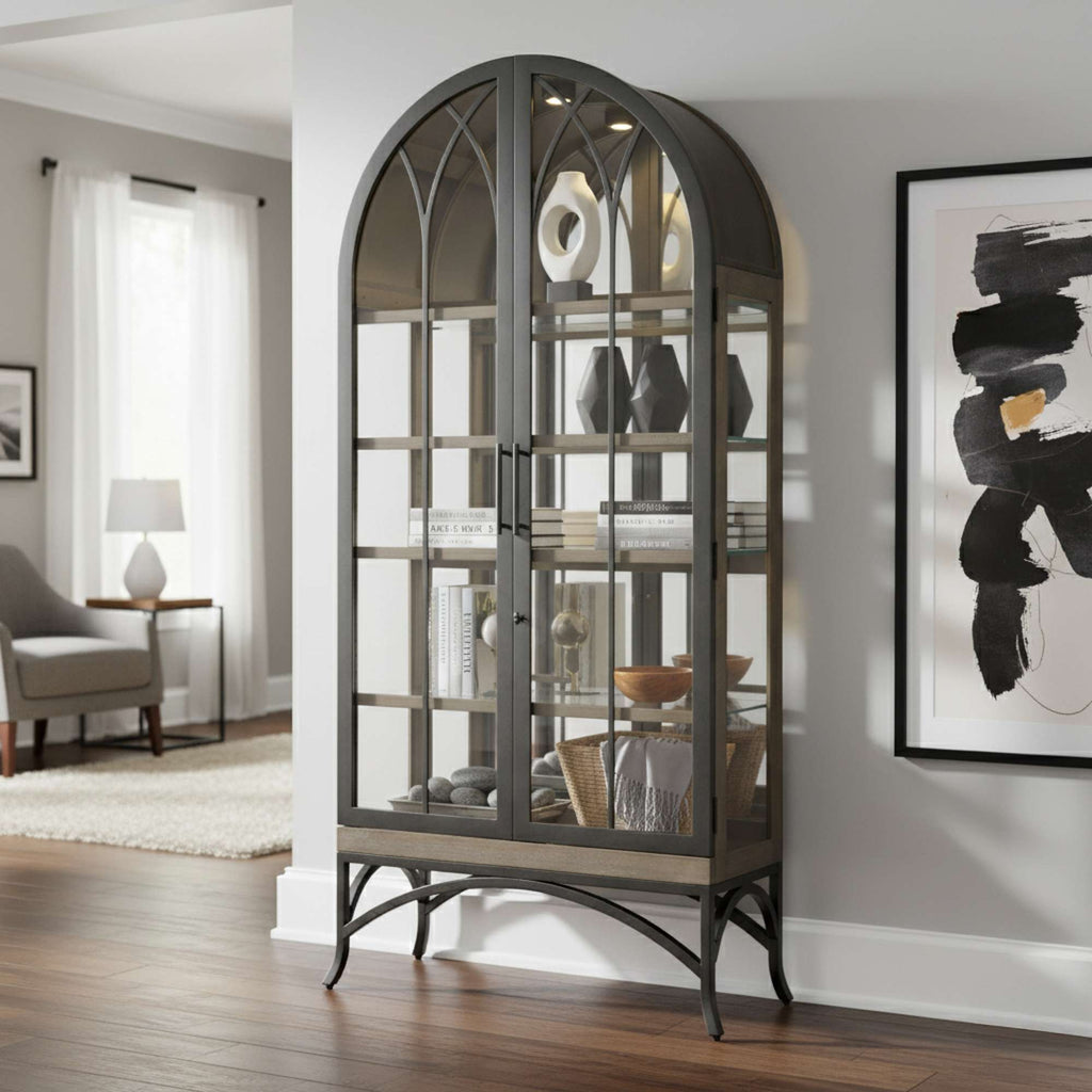 A stylish glass display cabinet with an arched design, showcasing decorative items in a modern living room.
