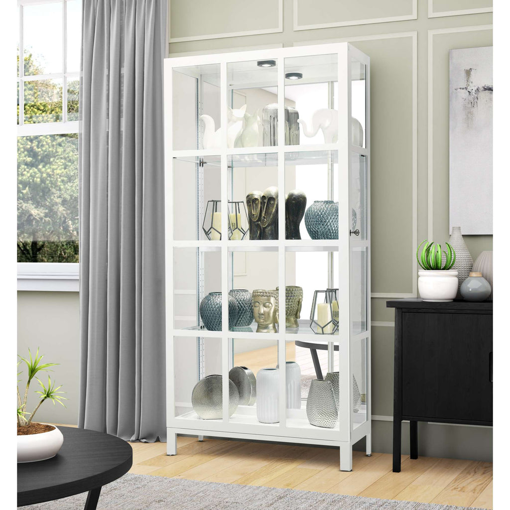 A modern white display cabinet with various decorative vases and objects inside, positioned near a window and a black side table.