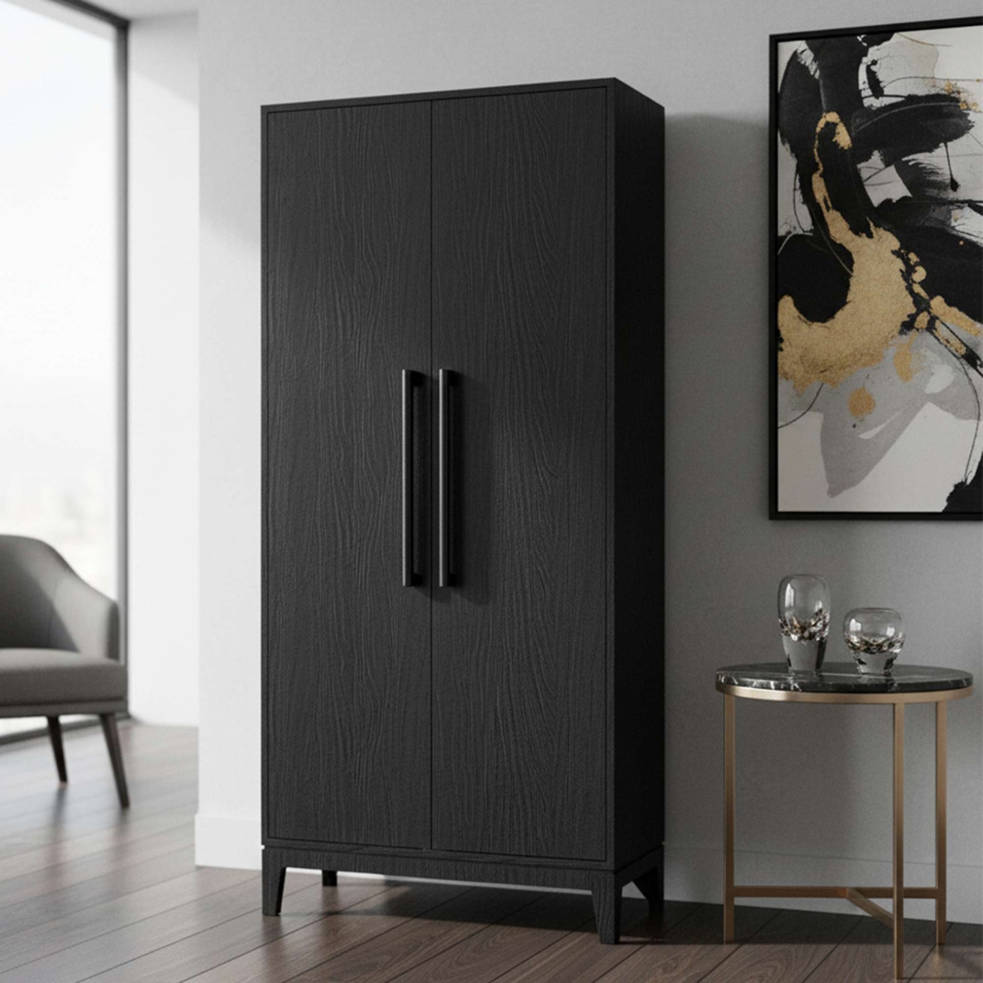 A modern black wardrobe positioned beside a small side table and abstract wall art.
