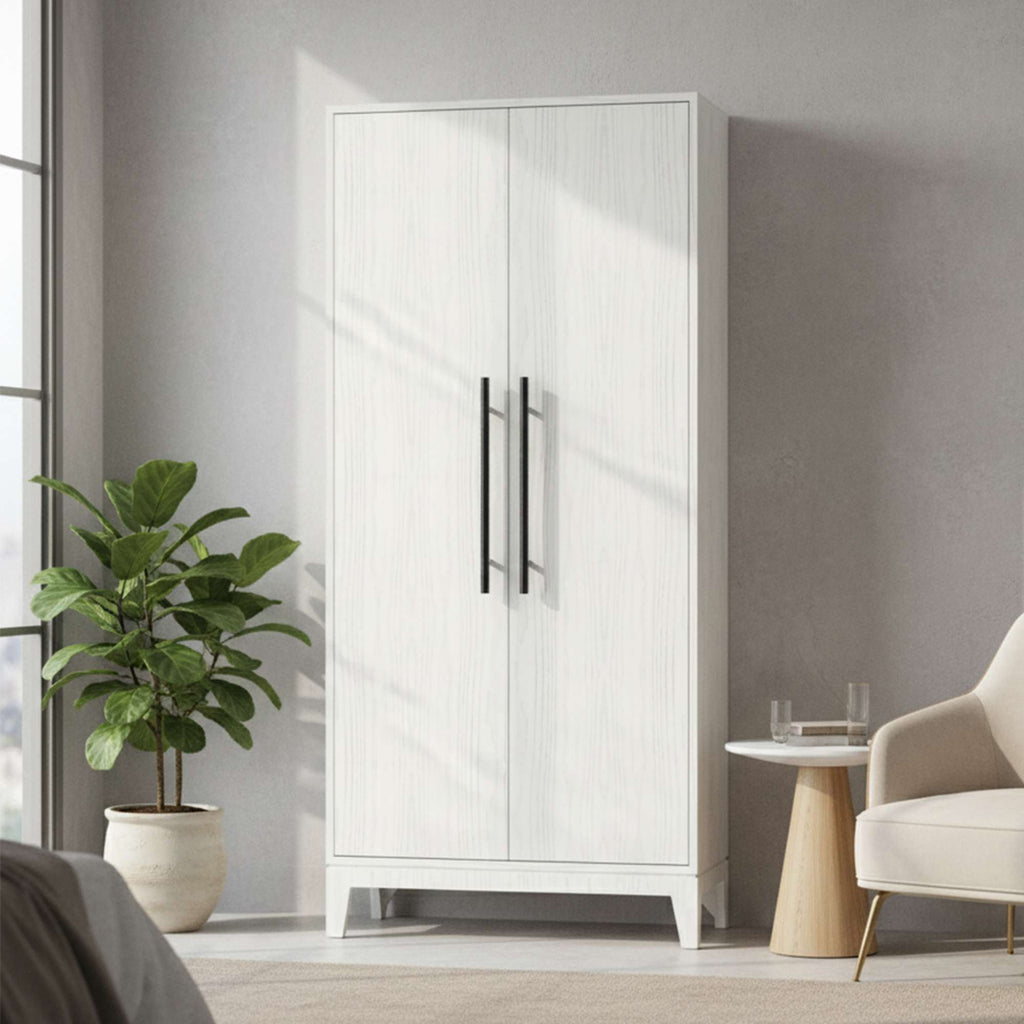 A modern white wardrobe with black handles next to a potted plant in a stylish interior.