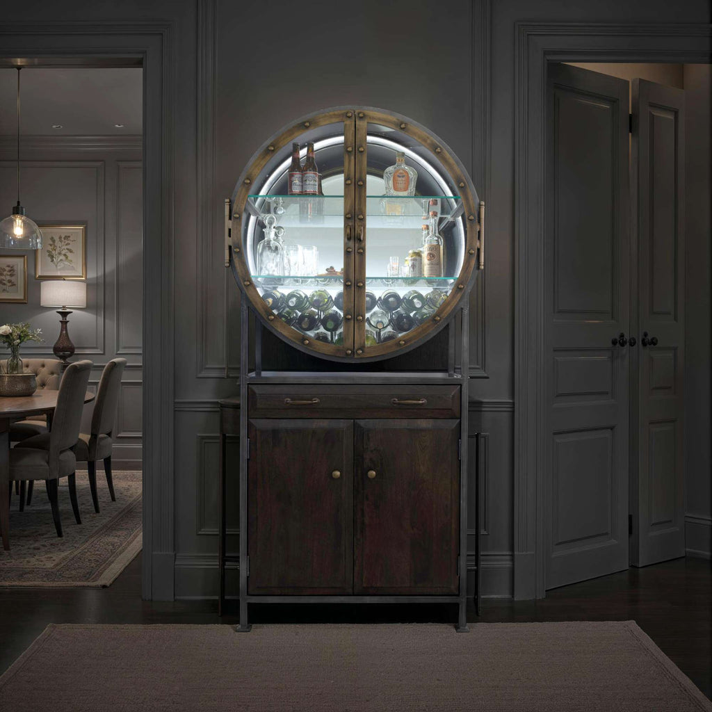 A stylish round display cabinet with glass doors, illuminated, set against a dark interior.
