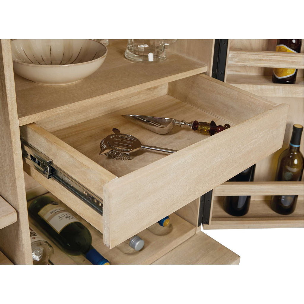 Open drawer with bar tools and bottles in a wooden cabinet.
