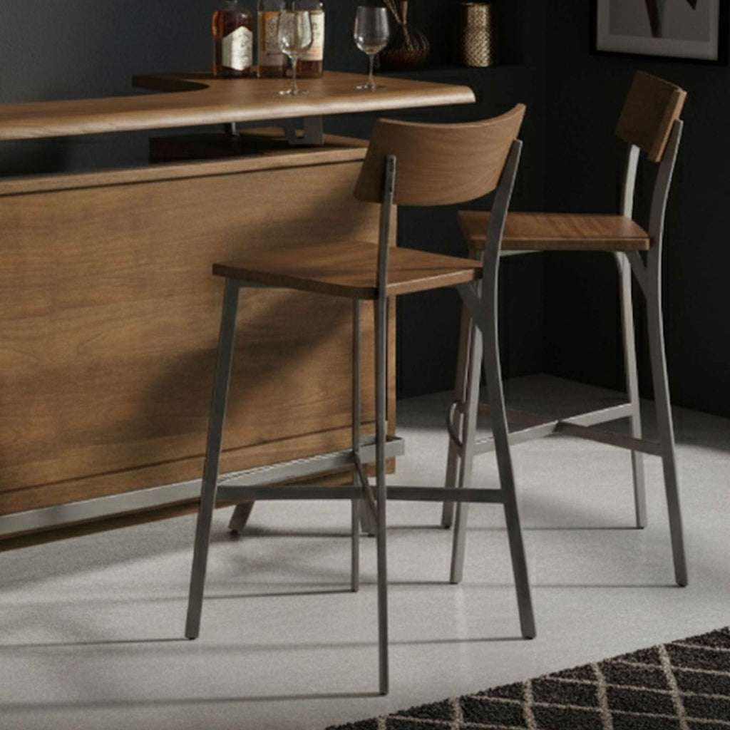 Two modern barstools beside a wooden bar with glasses and bottles.