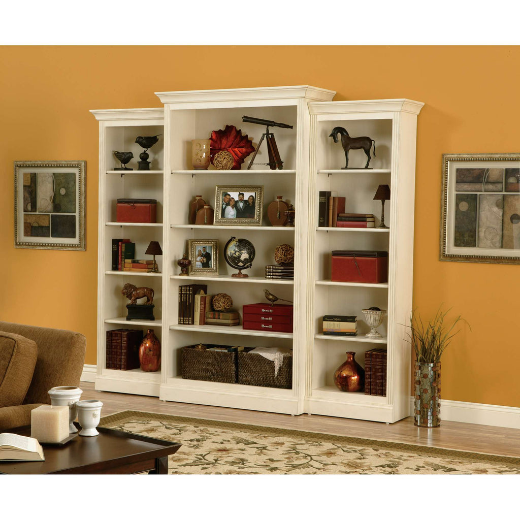 A stylish white bookcase filled with decorative items and books against an orange wall.