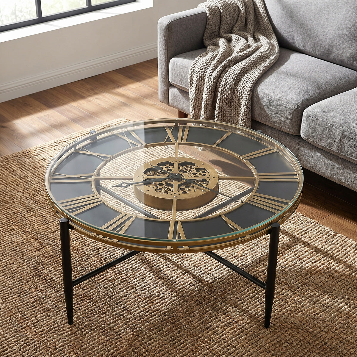 Round glass coffee table with gold roman numeral clock face in a living room setting.