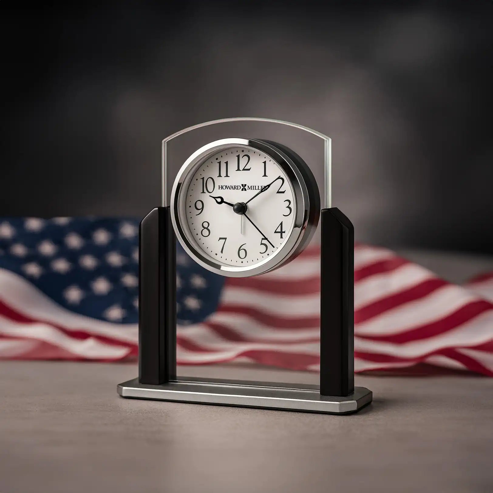 A decorative clock with a silver and black design in front of an American flag.