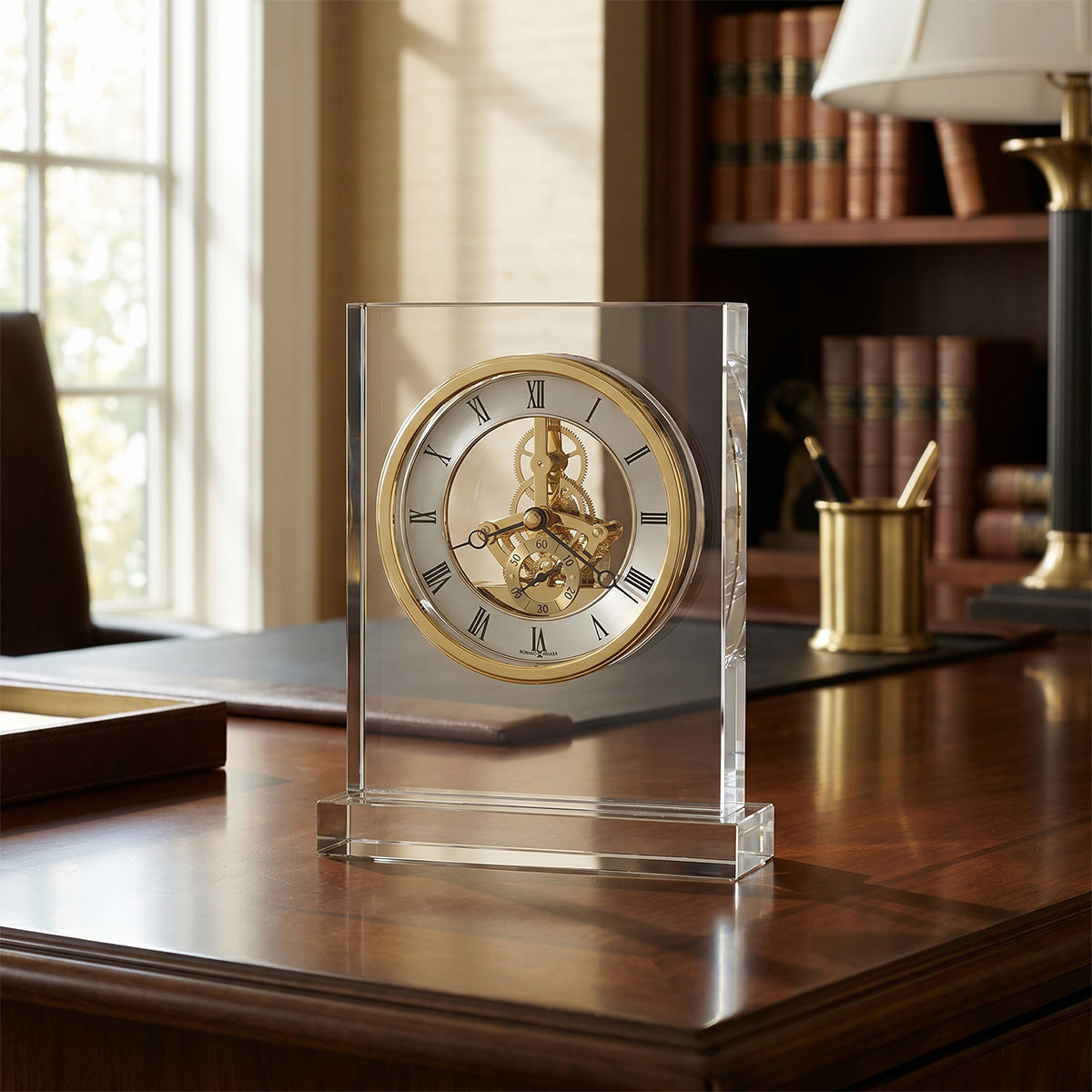 Decorative clock with gold face and clear crystal base on a wooden desk.