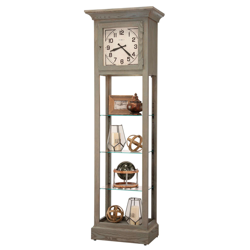 Tall, vintage-style floor clock with glass shelves displaying decorative items.