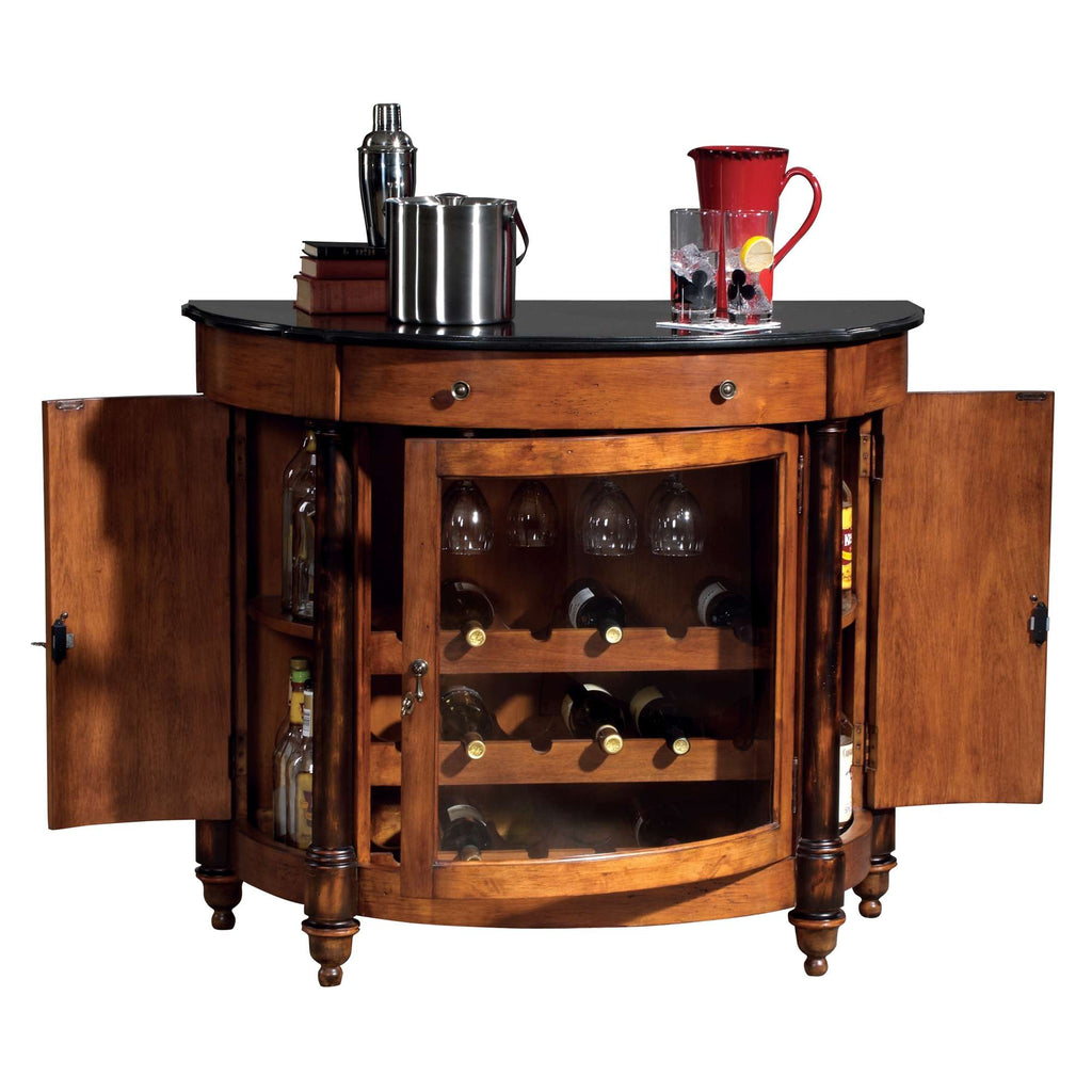 A wooden bar cabinet with a black top, featuring glass doors revealing shelves of glassware and bottles.