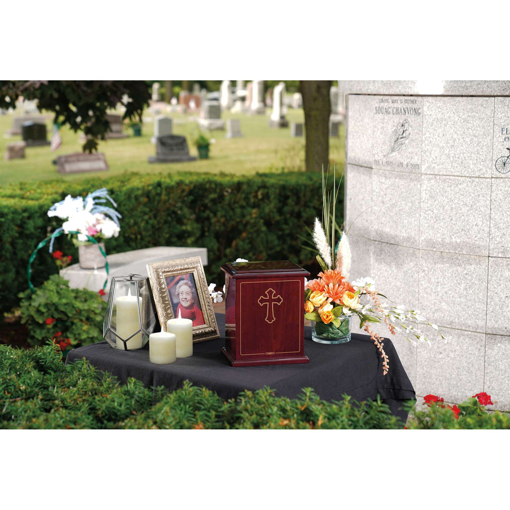 Memorial display with an urn, candles, a photo, and flowers at a gravesite
