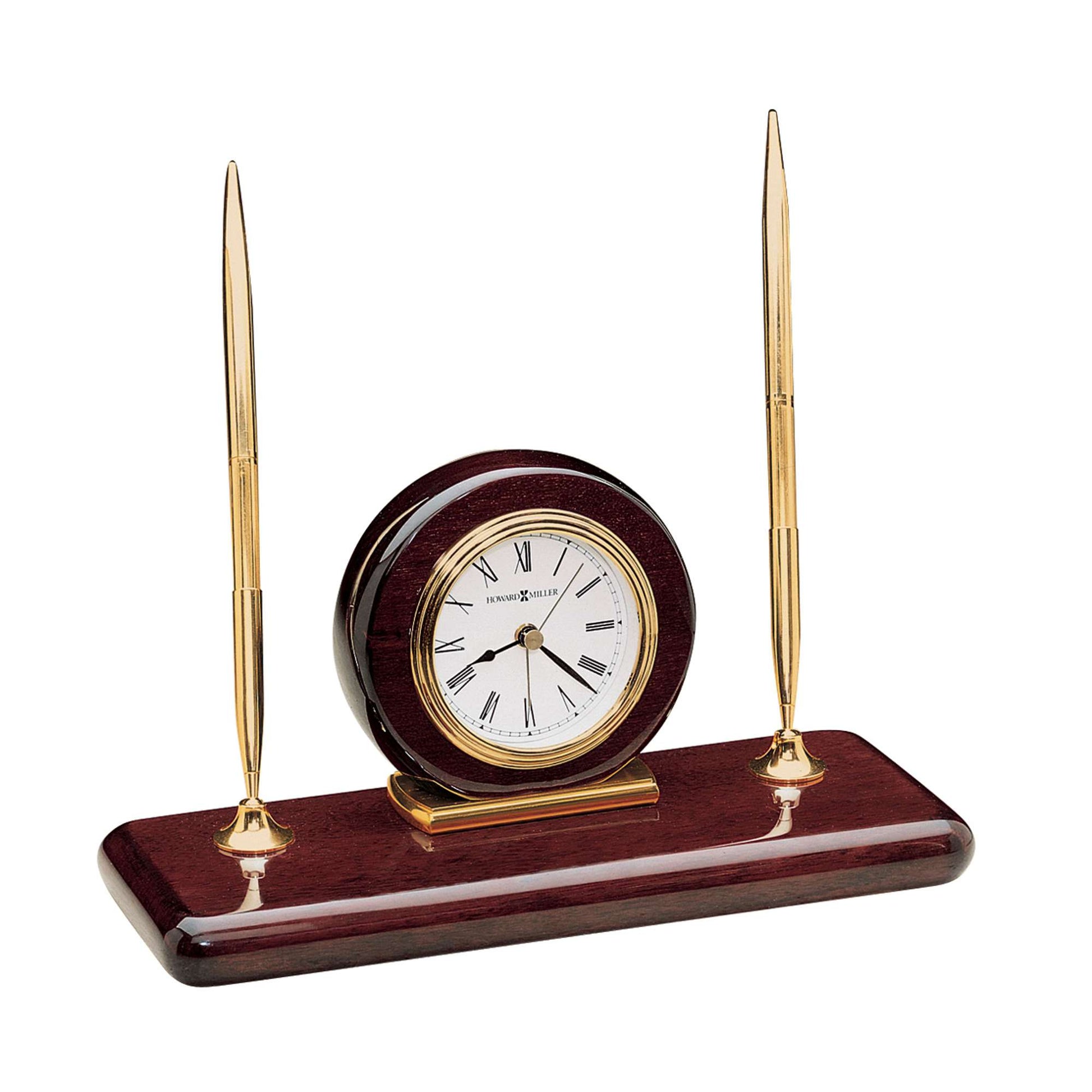 A decorative desk clock with two golden pens on a wooden base.