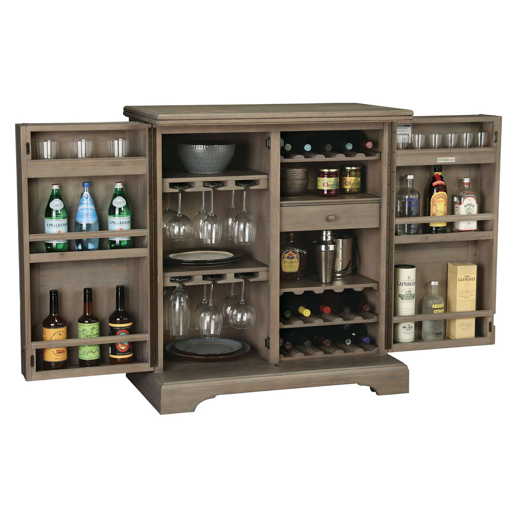 A wooden bar cabinet with open shelves containing bottles, glasses, and a serving bowl.
