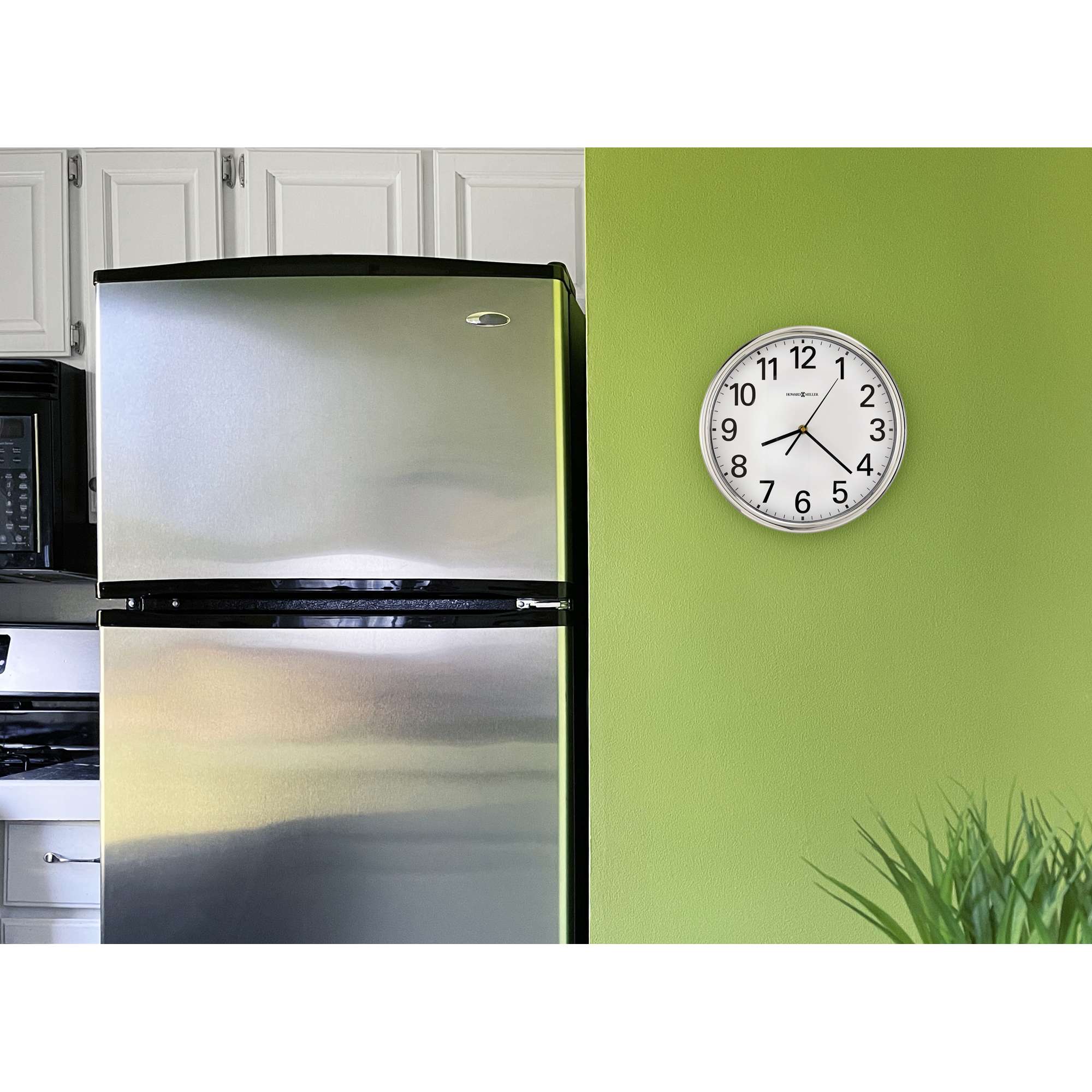 A modern kitchen with a stainless steel refrigerator and a round clock on a green wall.