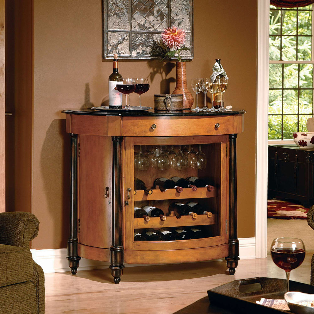 A wooden wine cabinet with a marble top, glassware, and wine bottles displayed, set in a cozy living room.