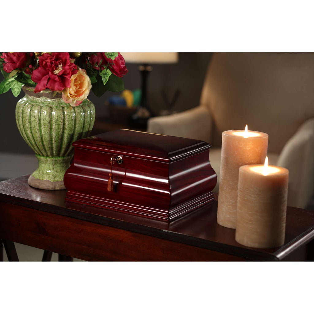 A decorative table featuring a wooden box, two candles, and a floral vase.