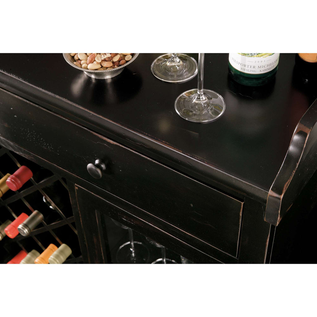 Close-up of a black wooden wine cabinet with wine bottles, glasses, and a bowl of nuts on top.