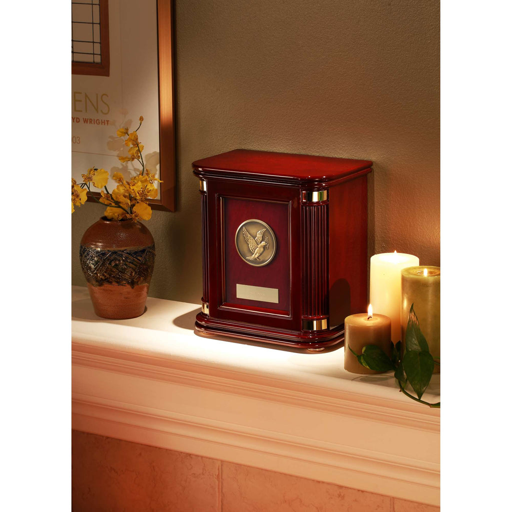 A decorative wooden urn on a mantle, accompanied by a vase with flowers and candles.