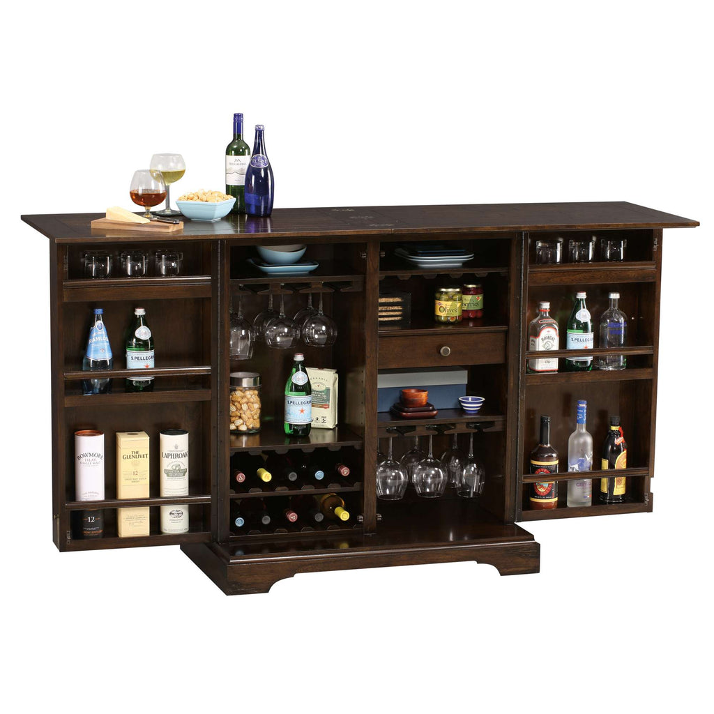 A wooden home bar with various bottles of alcohol, glassware, and snacks displayed.