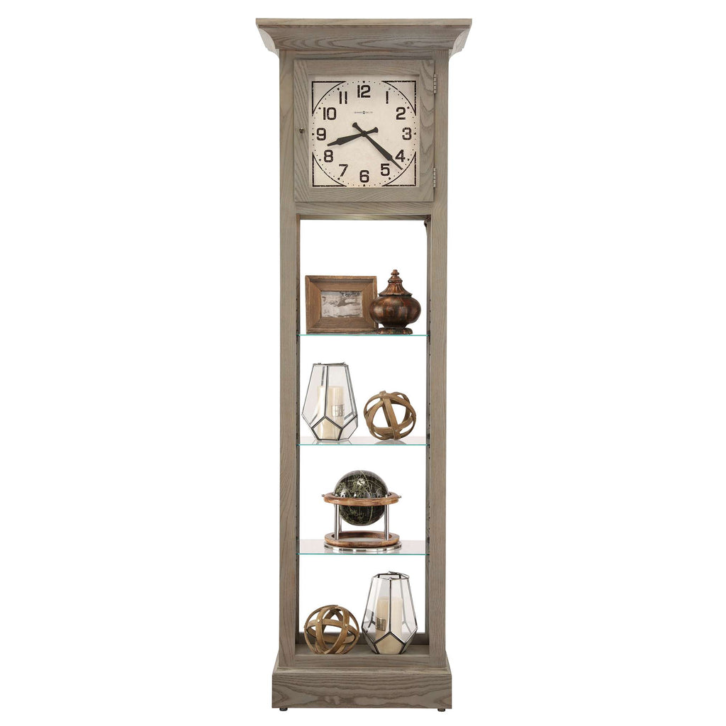 A tall, wooden clock cabinet with a clock at the top and decorative items displayed on glass shelves.