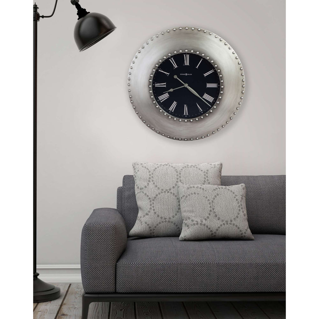 Stylish living room setup featuring a gray sofa with decorative pillows, a modern circular wall clock, and a standing lamp.