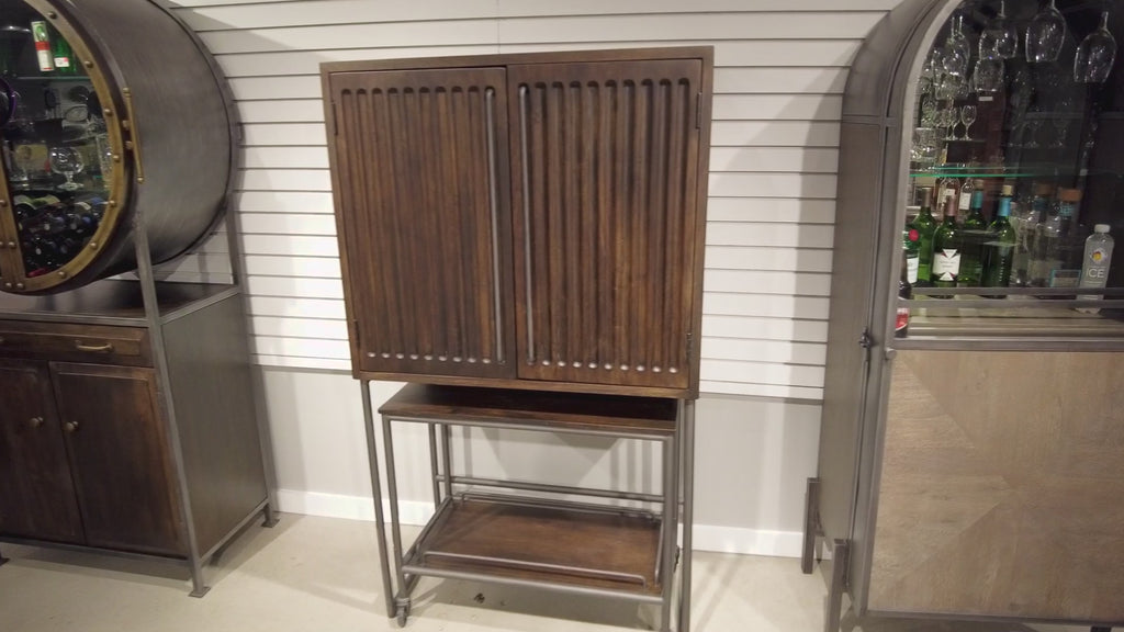A wooden cabinet with louvered doors, displayed in a showroom setting.