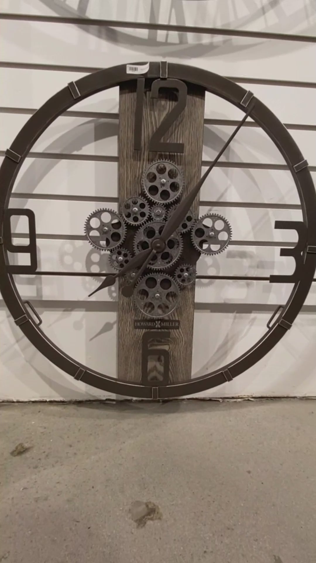 A large wall clock with a gear design and wooden background.
