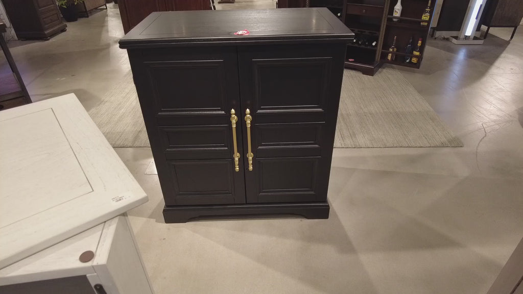 Black wooden cabinet with gold handles in a furniture store