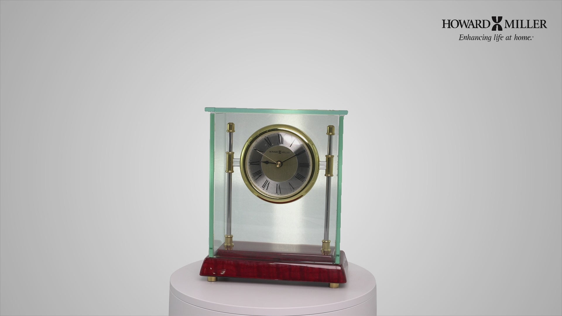 A decorative glass and brass clock on a maroon base.