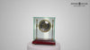 A decorative glass and brass clock on a maroon base.
