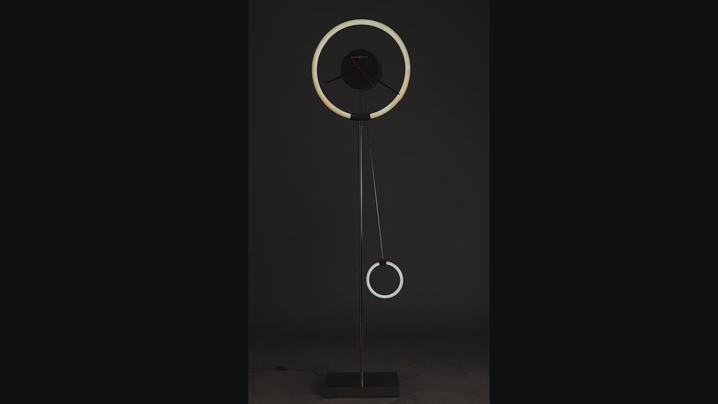 Modern floor lamp with a circular design and hanging ring elements against a dark background.