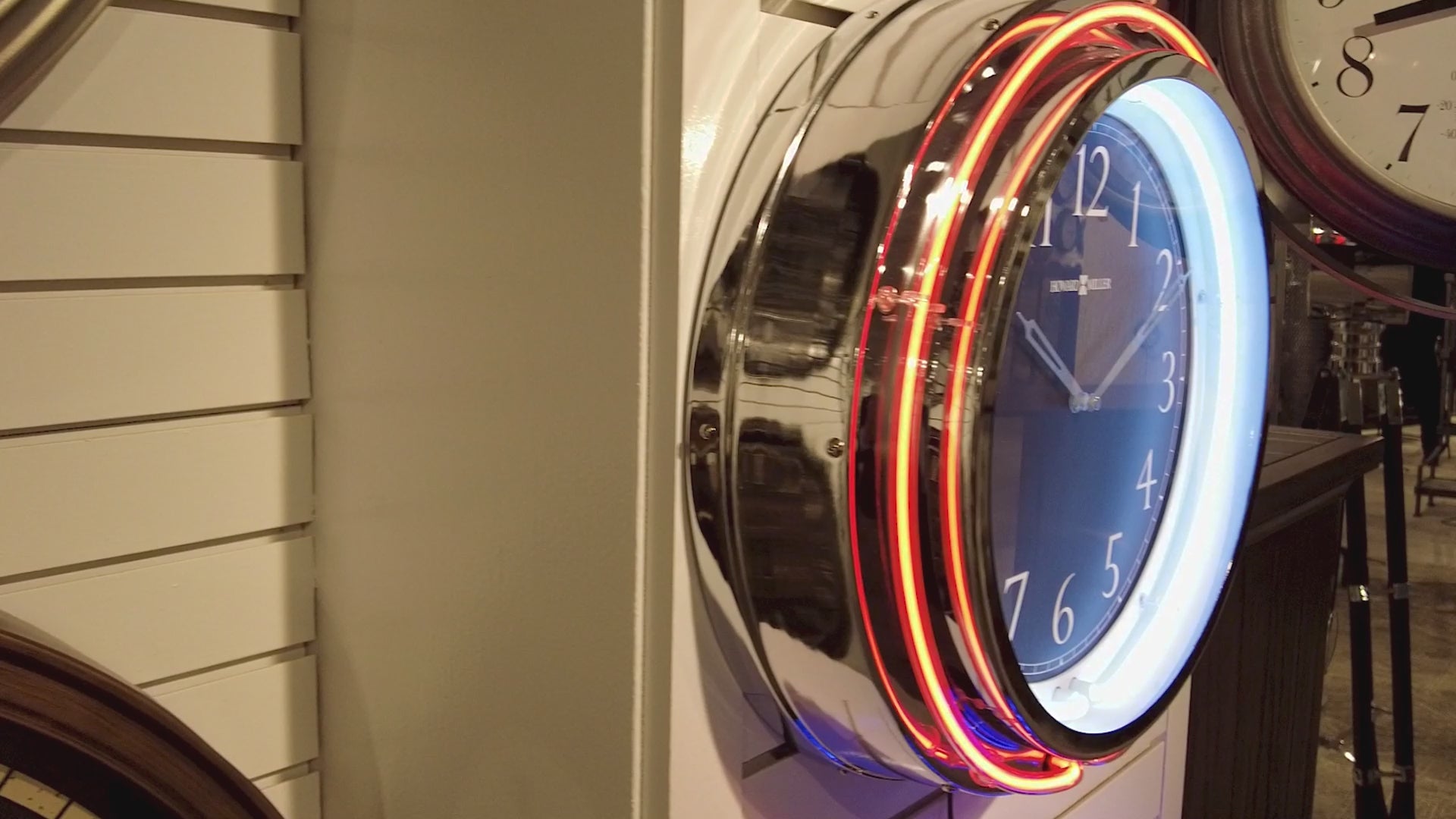 Close-up of a round, modern clock with a blue face and neon-like lighting.