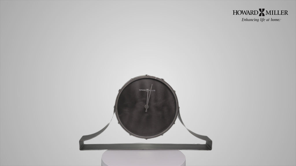 A modern wall clock with a circular black face and sleek gray support.