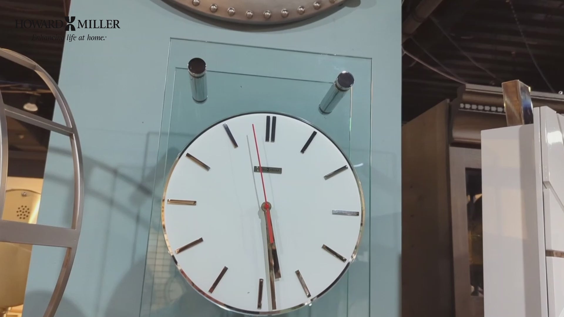 A large wall clock with a white face, black hour markers, and a red second hand.