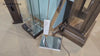 A close-up view of a modern lamp base with a mirrored surface, surrounded by glass and wooden furniture.