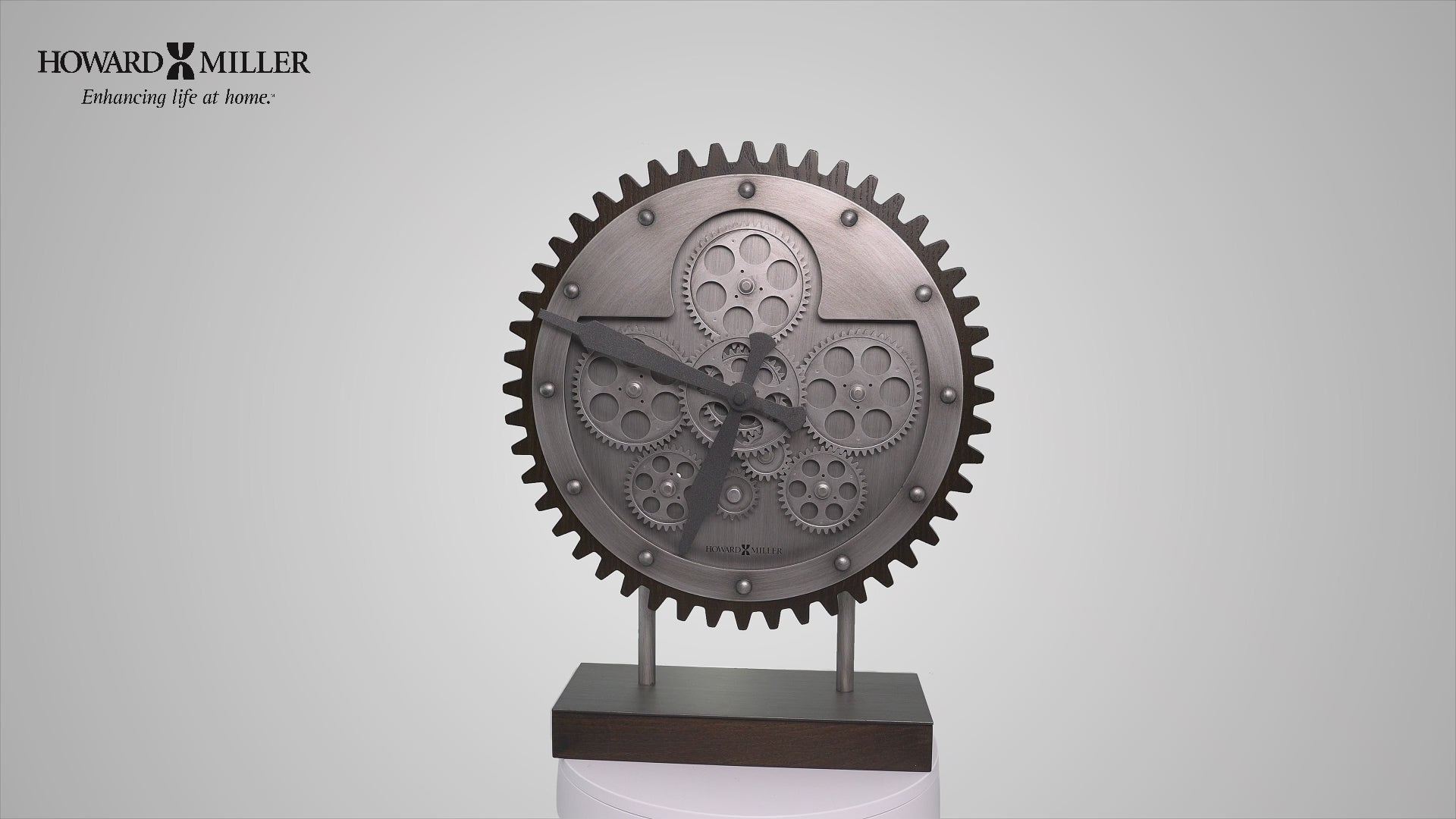 A decorative clock designed as a gear, featuring intricate details, mounted on a stand.