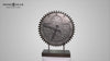 A decorative clock designed as a gear, featuring intricate details, mounted on a stand.